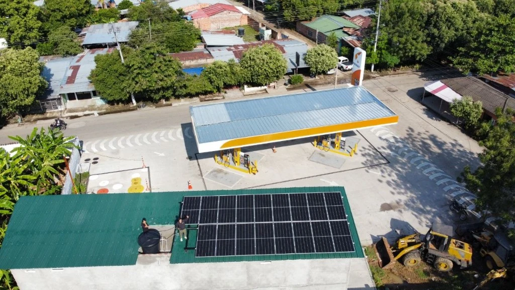 Vista aérea de paneles solares junto a una estación de servicio